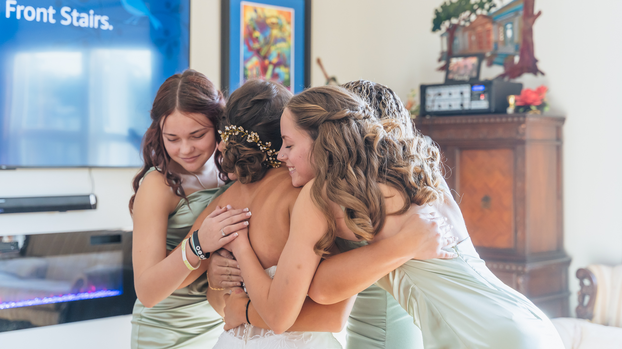 Bride being tenderly embraced by bridesmaids