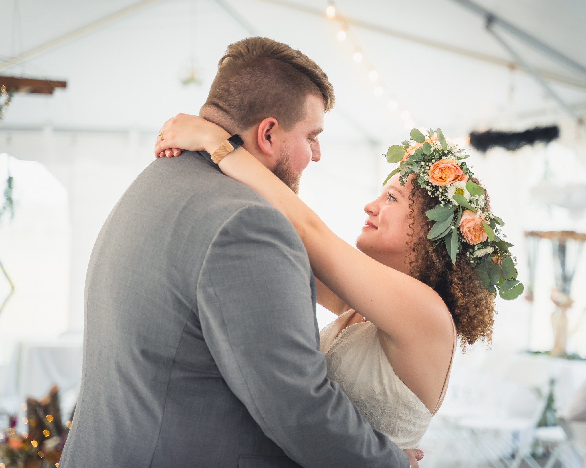Bride with flower crown looking longingly and intimately into her Mississippi groom's eyes during their first dance in a tent wedding.