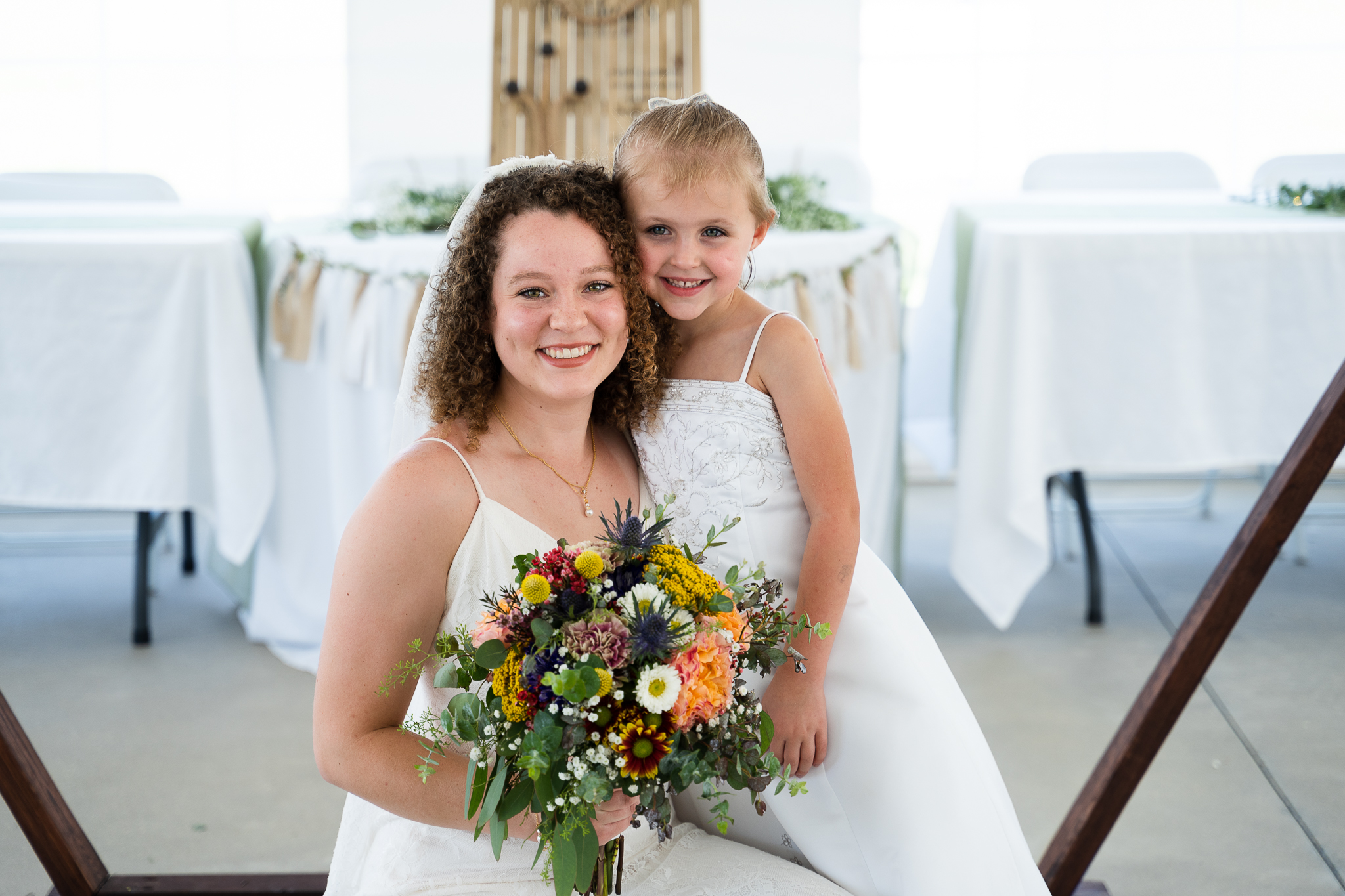 Bride and flower girl posing for portrait at christian tent wedding