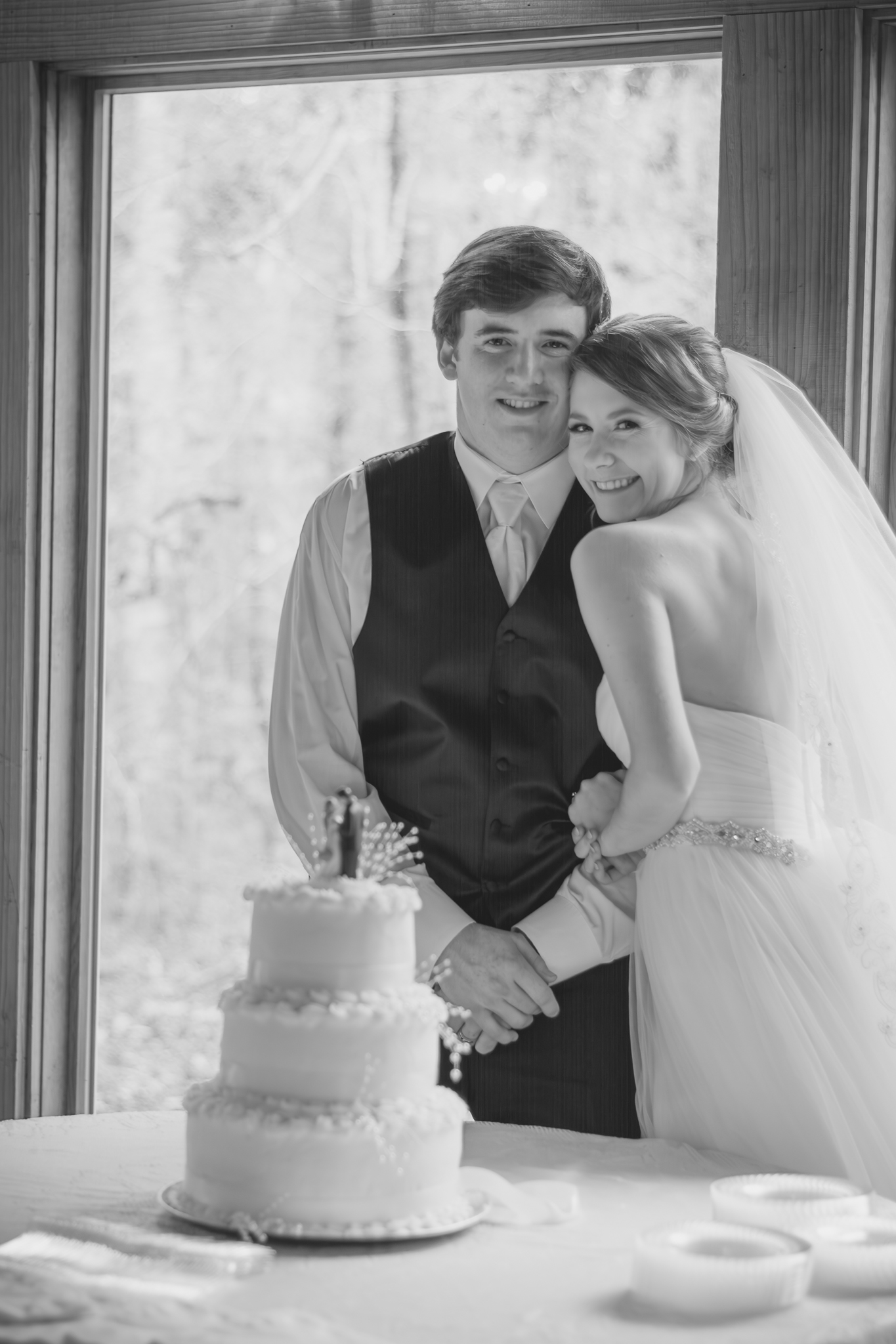 Bride and Groom posing for a photo in front of their wedding cake