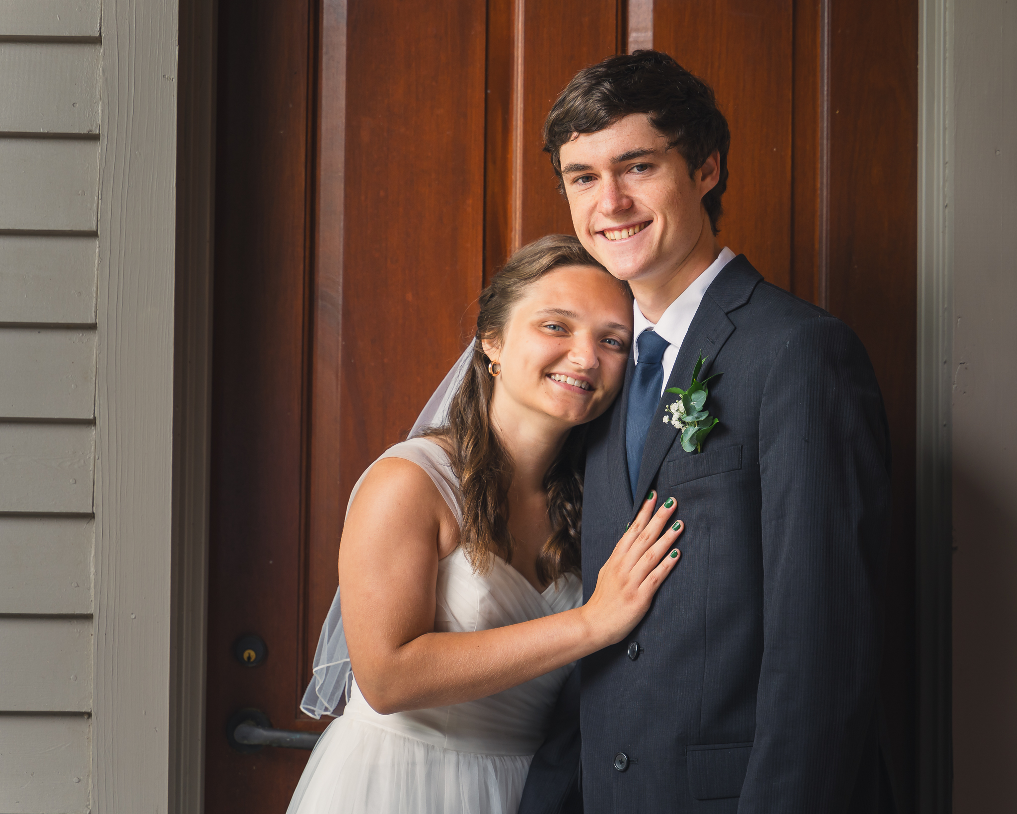 Clinton, MS Bride and Groom resting on each other in front of a door at a wedding venue