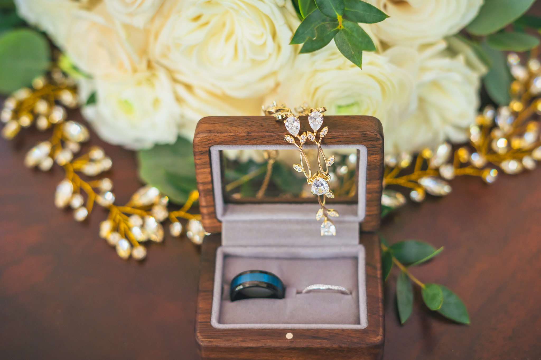 Detail photo of wedding rings and wedding florals with bride's jewelry in focus